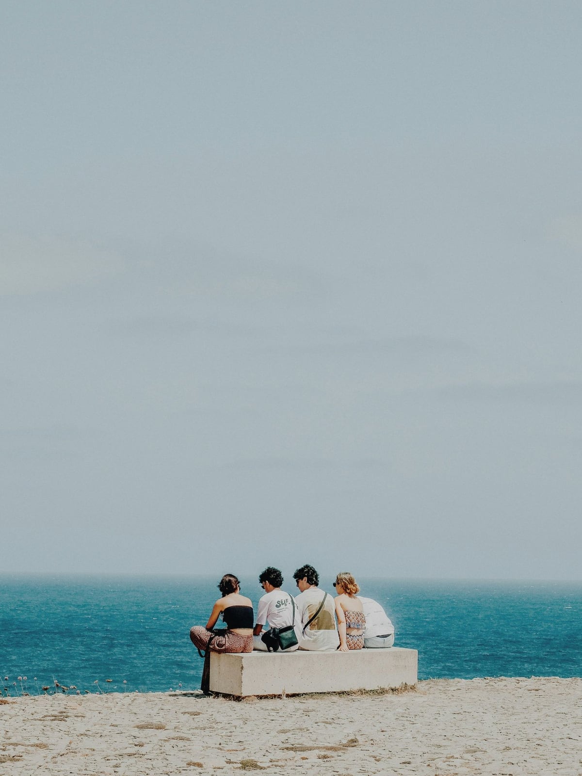 Four friends on a cliffside bench looking out to sea